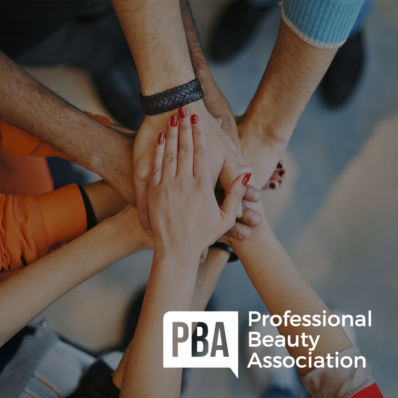 Professional Beauty Association logo over photo of multiple hands on top of each other.