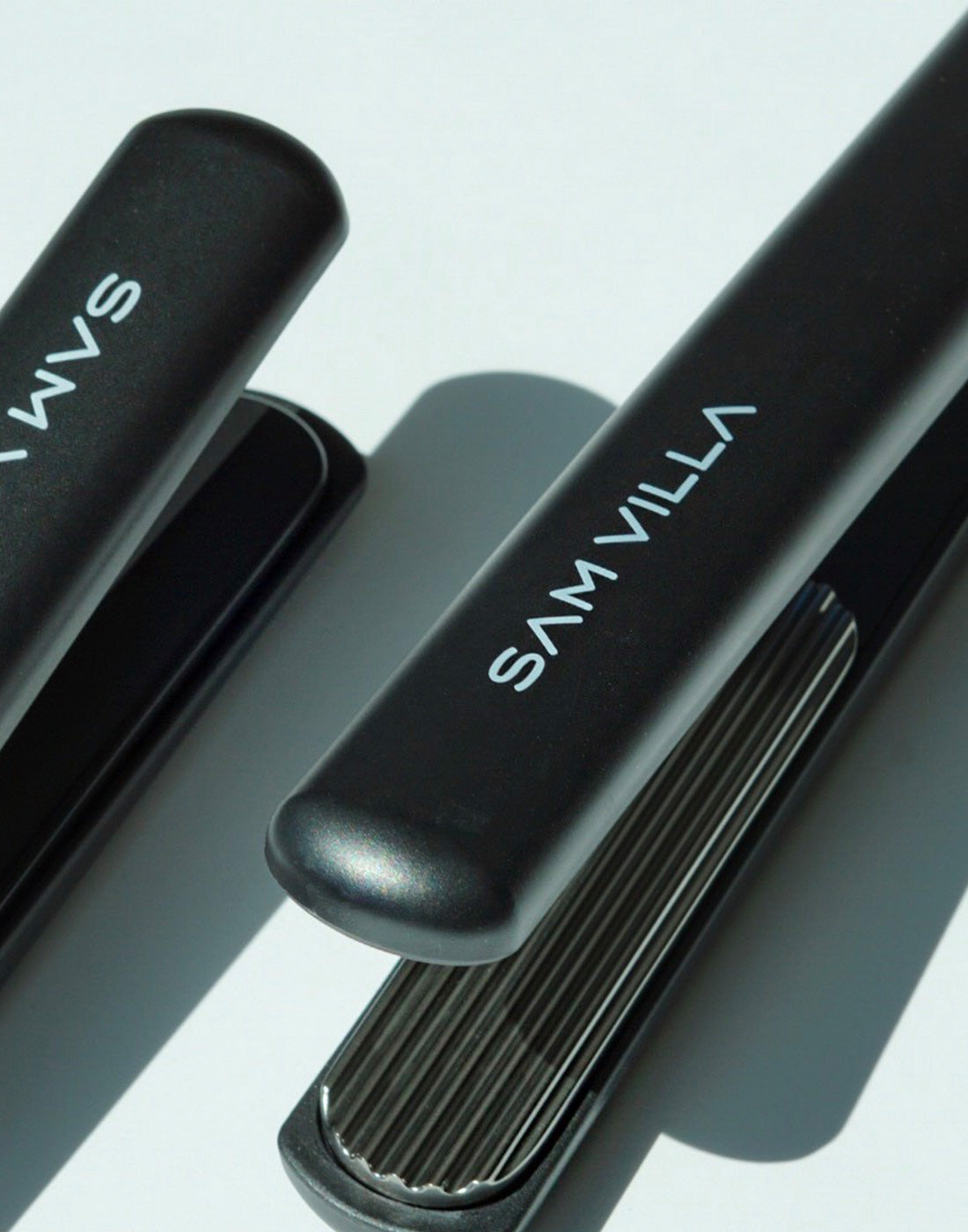 One SLEEKR® Professional Flat Iron and one TEXTUR® Professional Texturizing Iron positioned next to each other with shadows.