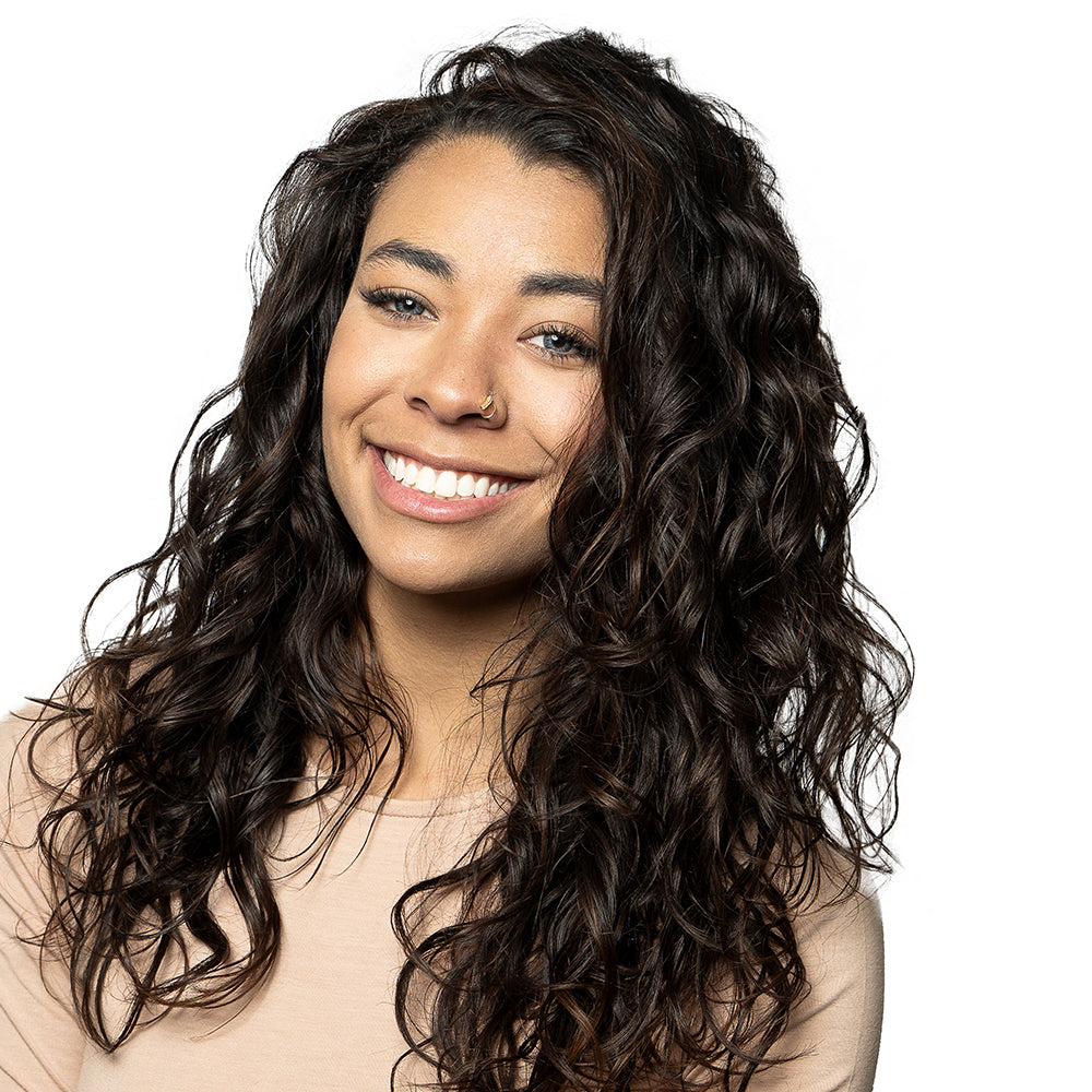 Brunette woman smiling with tousled, curly hair.